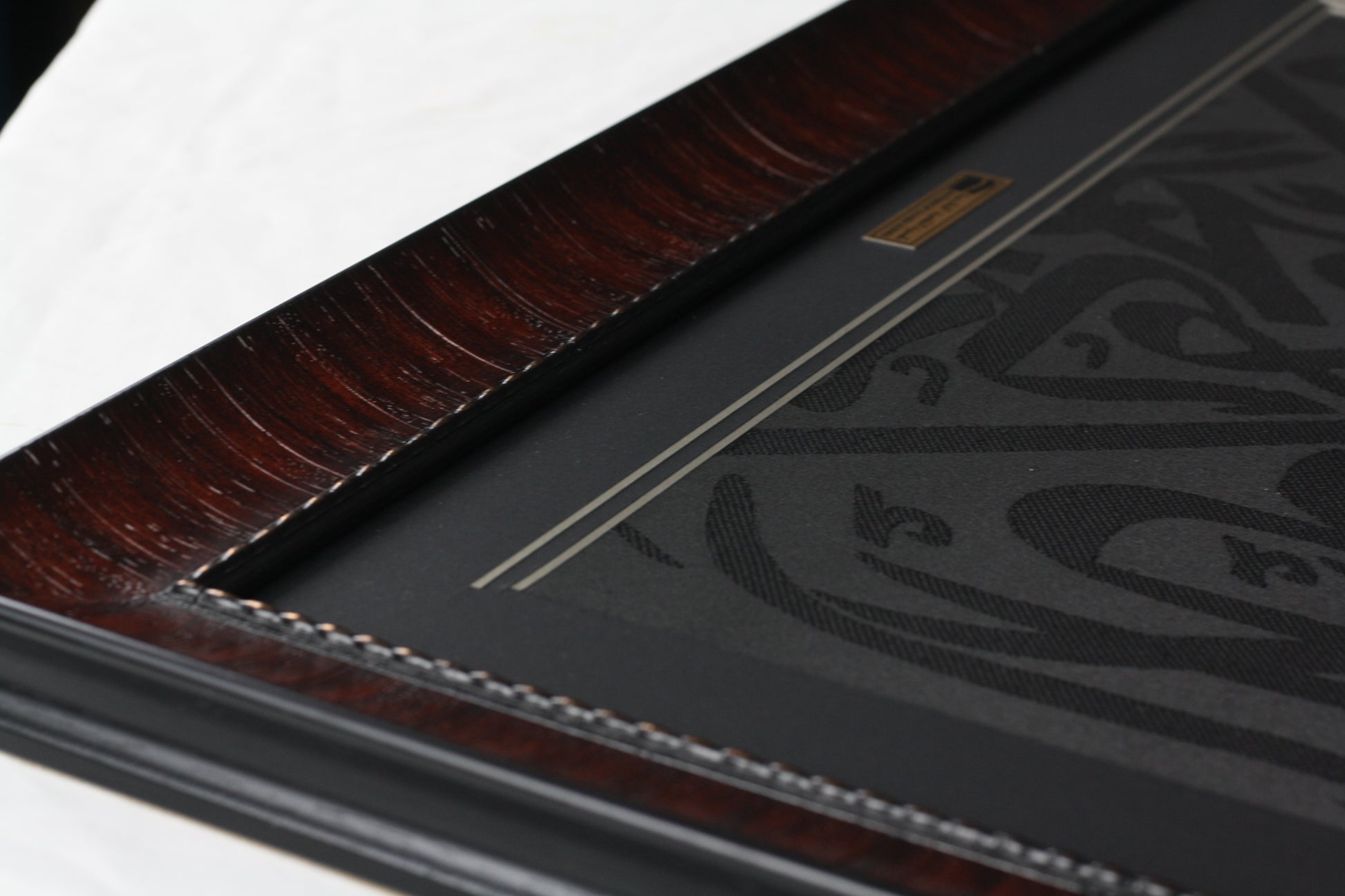 Close-up of a black leather-bound book with embossed design on a white background